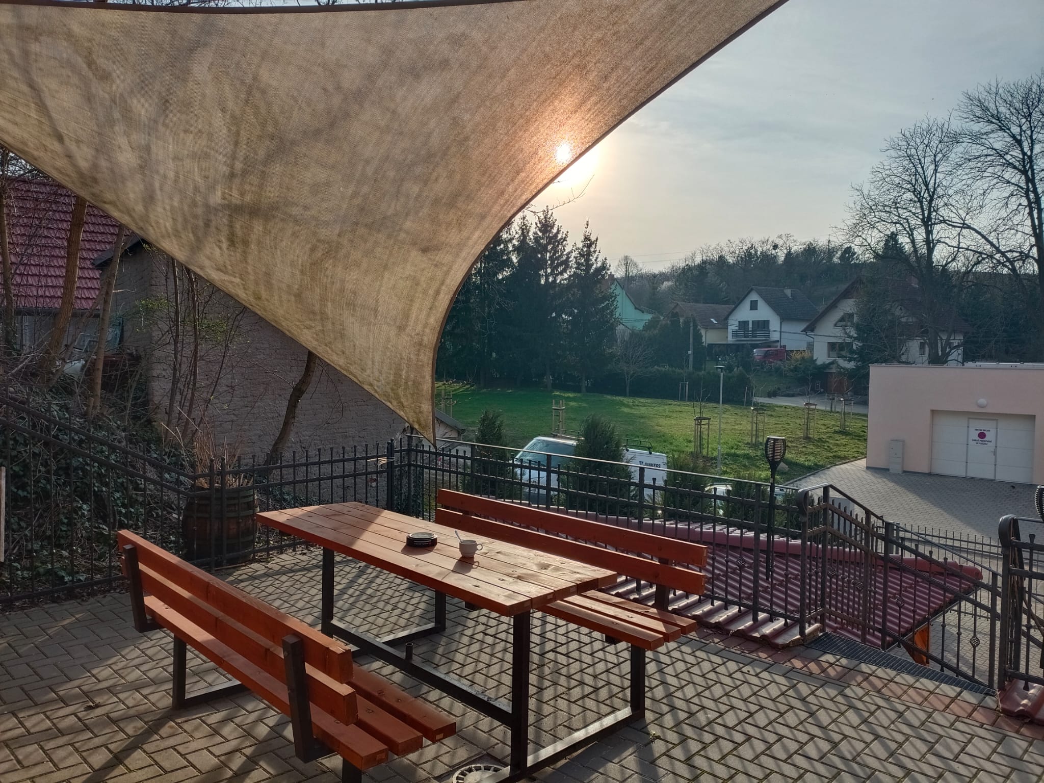 Terasa penzionu s plachtou proti slunci, dřevěné posezení s výhledem do údolí